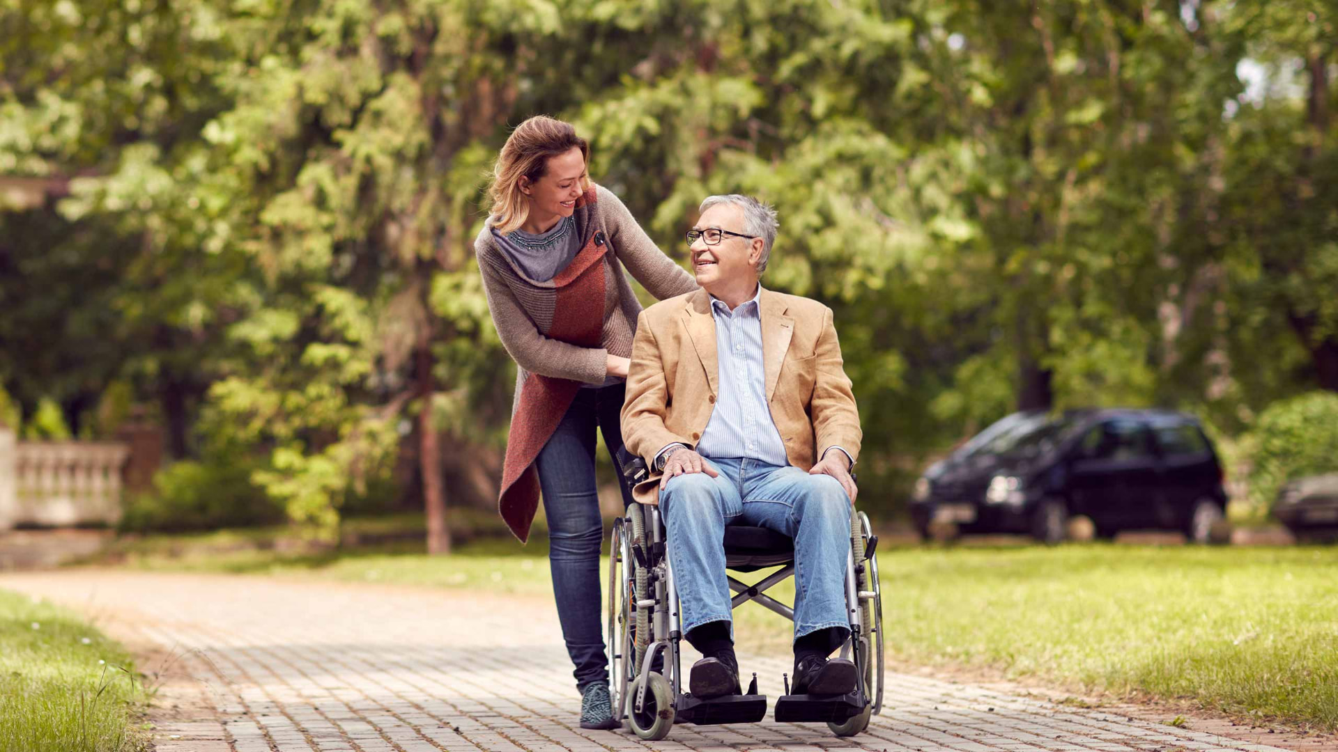 A support worker walking outdoors with a man in a wheelchair